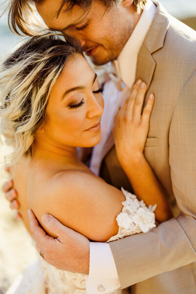 bride and groom embracing while eyes are closed and bride is turned toward the camera