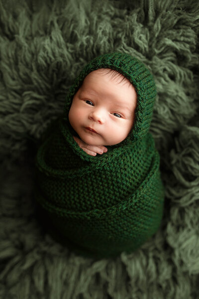 Beautiful baby boy wrapped in a hand knitted  green wrap with matching bonnet.