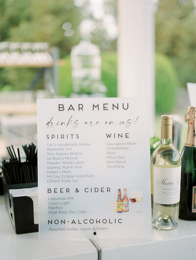 Bar menu at wedding reception with wine on display.