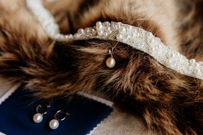 Beaded and pearl bridal accessories lay atop  fur shawl