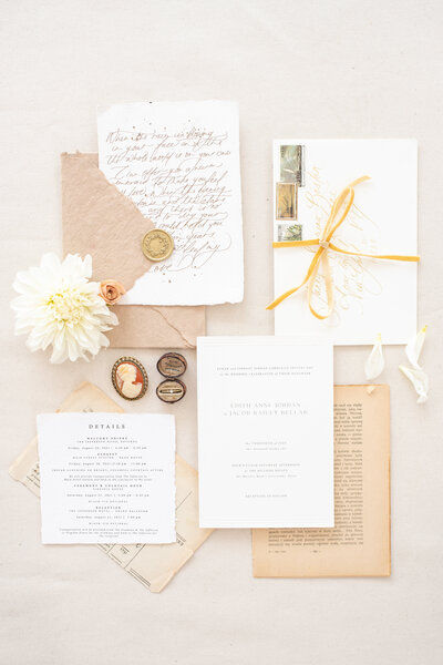Beautiful vintage flatlay with handwritten vows, a classic invitation suite, an invory Cameo and a vintage ring box with a stunning diamond ring.