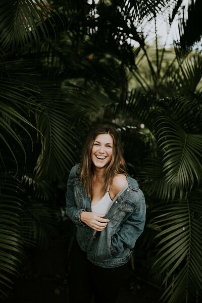 Jackie laughing in a jean jacket in a Hawaii jungle