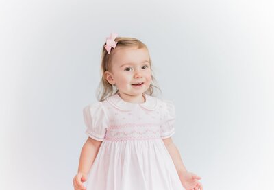 Toddler in a pink dress with a bow in her hair.