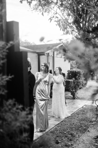 A candid moment in black and white with a bridesmaid watching a first look and getting emotional 