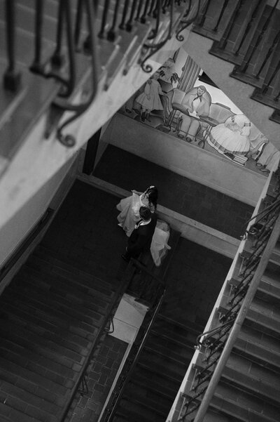 Photo of bride and groom walking up the stairs at the Julia Ideson Building in Houston, TX