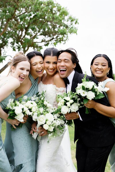 A newlywed couple smiling with their wedding party 