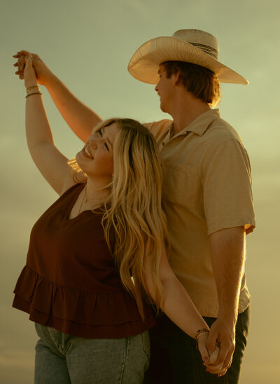 engaged couple posing infront of a barn with man kissing womans forehead