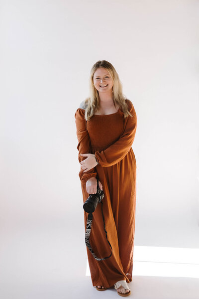 Travel elopement photographer smiles with her camera in hand, ready to capture adventurous love stories across Utah and beyond.