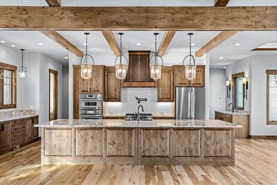 a rustic kitchen with wood beams and custom pendants