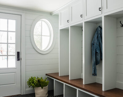 Boston Home Magazine's web feature highlights our custom cabinetry at the Needham project: a classic home with light grey and walnut mudroom details, featuring an elegant oval window.