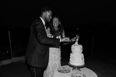 Chase and Keiyana cutting their wedding cake, in black and white.