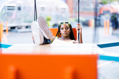 Teen in swing with feet on table for 90s theme shoot