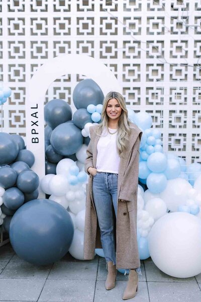 Woman poses in front of Hart and Main's breezeblock wall for a company party