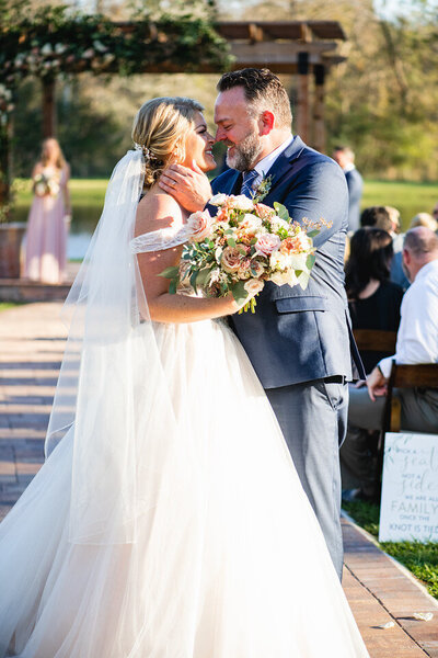 Couple shares a kiss while walking back down the aisle after being married at Cypress Creek Farmhouse Orlando wedding venue.