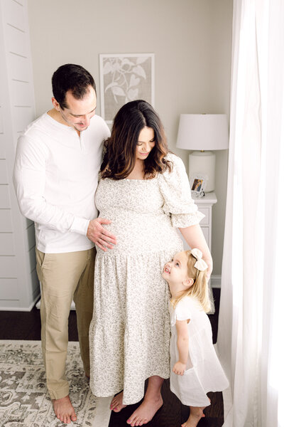 Pregnant mother standing in her home with husband and toddler by her side taken by Cincinnati Newborn Photographer