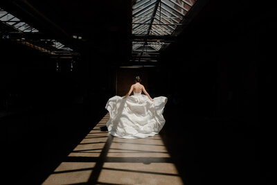 A bride fluffs her dress while walking in the sunlight at Morgan MFG in Chicago, IL 