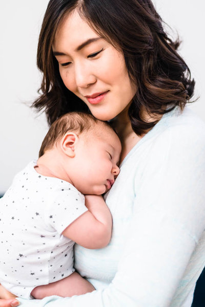 Korean mother snuggling newborn