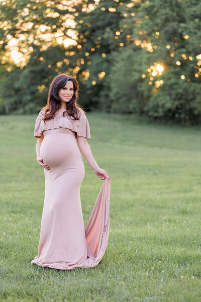 A mother-to-be leaning against a tree at the park for a maternity session.