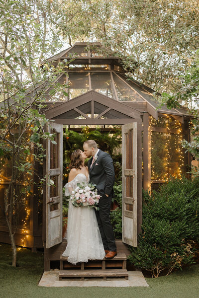 Wedding couple kissing in front of a greenshouse