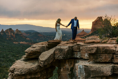 bride and groom walking on red rocks in sedona