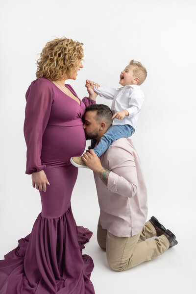 studio maternity portrait of a beautiful african american expecting mama wearing a long green maternity gown and