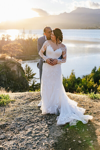 Columbia River Gorge elopement featuring a bride with a long sleeve lace dress with her groom kissing her cheek.