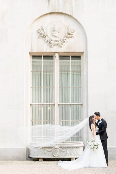 outside of the Mayflower hotel wedding venue on the sidewalk is the Bride and Groom kissing