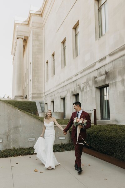 bride and groom holding hands smiling at each other