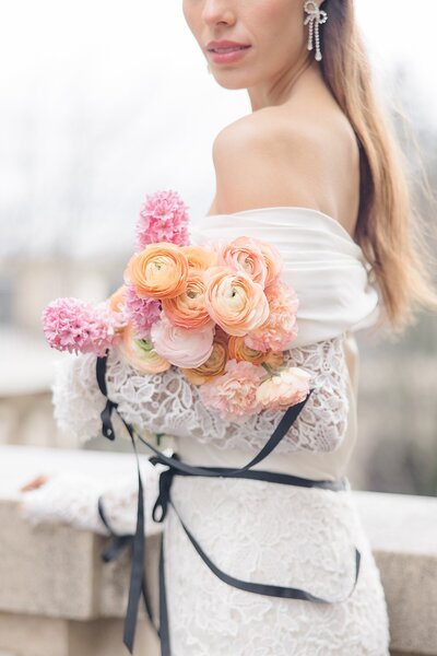 Paris elopement, with a bride holding a peach and pink bouquet, and wearing a long lace gown