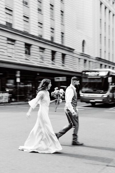 Couple having wedding photos in Brisbane City running across the road at some traffic lights - Brisbane Wedding Photographer