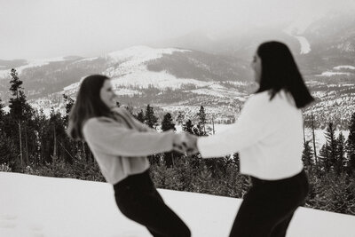 Blurred black and white image of couple dancing in the snow with Breckenridge mountains behind them.