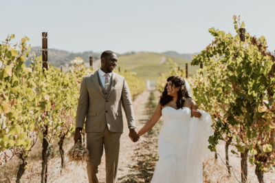 Bride and groom walking hand-in-hand in a sunny vineyard during their adventure elopement in Sonoma, CA