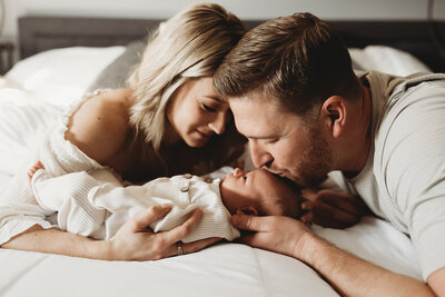 During a Bismarck In-Home newborn session a momma and dad share a tender moment with their newborn baby girl