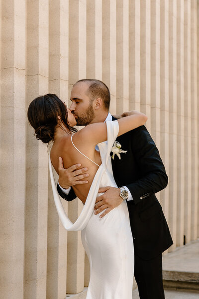Groom embraces his bride in a modern architectural corridor at Acre Resort, Mexico wedding.