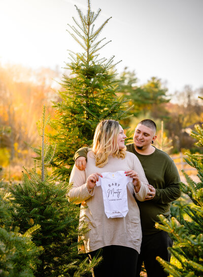 photo of a mom and dad to be at a christmas tree farm session in Stow MA