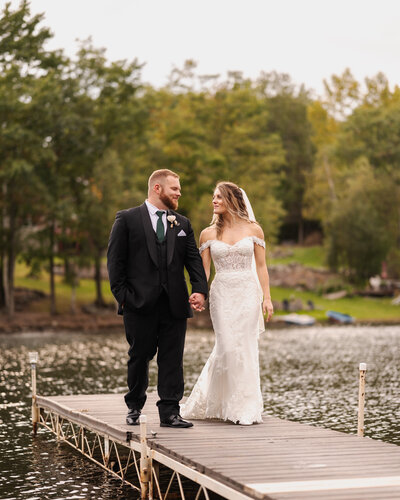 A bride and groom walking back from the end of the dock at Old Daley on Crooked Lake in Averill Park, NY.