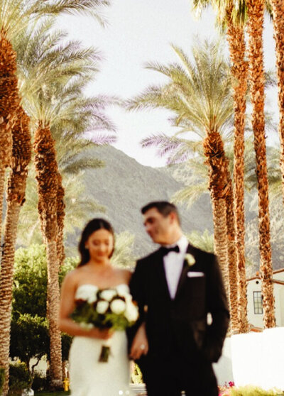 bride and groom walking with palm trees behind them