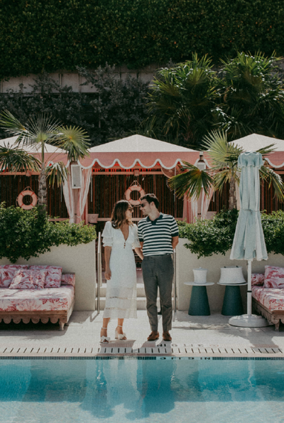 couple smiling at eachother in front of pool