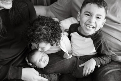Sister kissing newborn baby brother during photo session in Elmhurst, IL