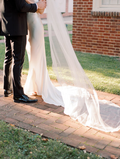 bride and groom hug while the sunlit veil blows in the wind
