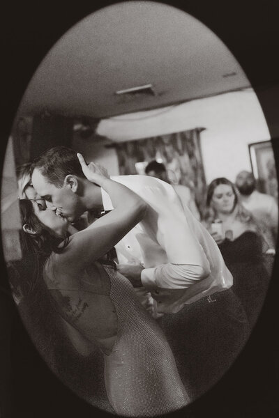 A passionate kiss on the dance floor, framed in an intimate, vintage-style vignette, capturing the raw emotion and joy of a wedding reception celebration.