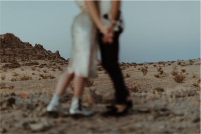 couple-holding-hands-in-desert@2x