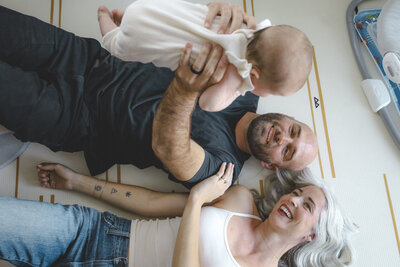 Vista family photographer capturing parents laughing and playing with their baby at home