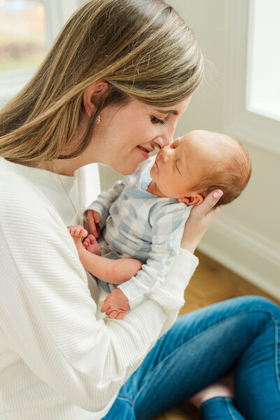 Mother holding her newborn baby close, gently touching noses in a tender and loving moment