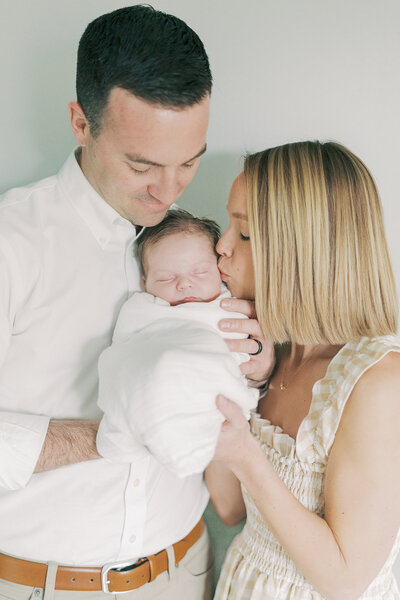 parents kissing cheek of newborn