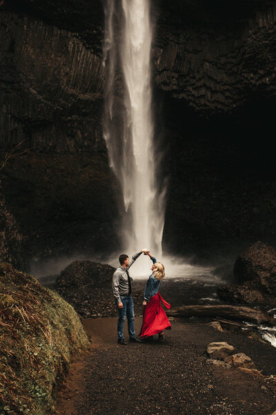 boy twirling girl at waterfall