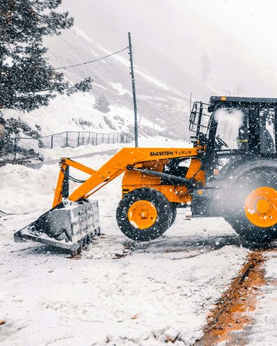 Yellow excevator removing snow comemrcial property