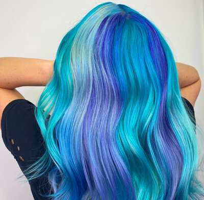 Image of client with hair that has been dyed various hues of blue. 