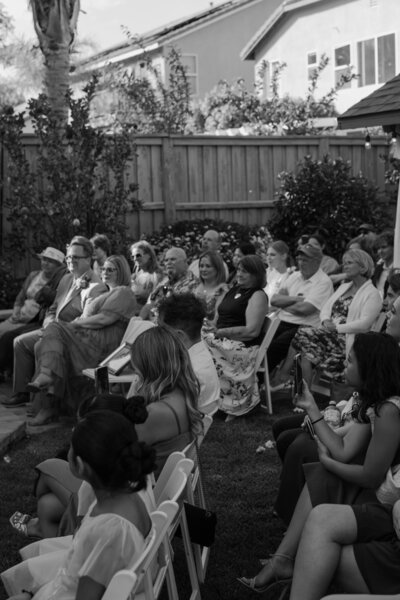 Family and friends gathered at the ceremony for Regan and Yered's backyard wedding in black and white.