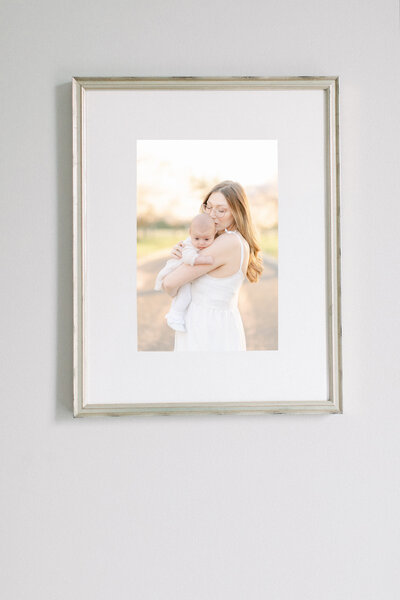 Minimal gold framed wall portrait of a mom kissing her baby